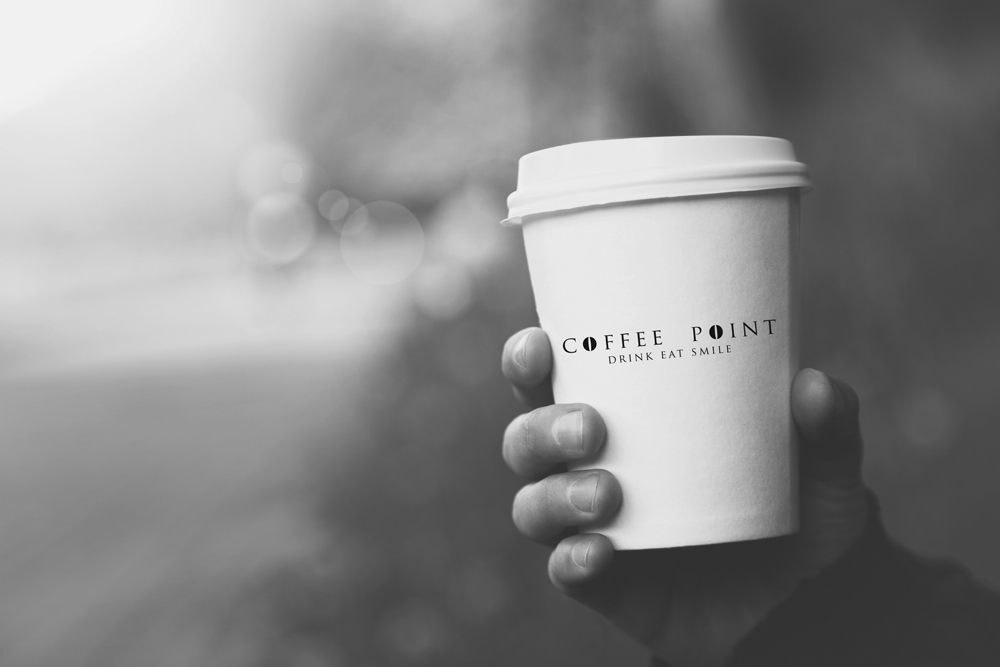 hand holding paper cup of coffee on natural morning background